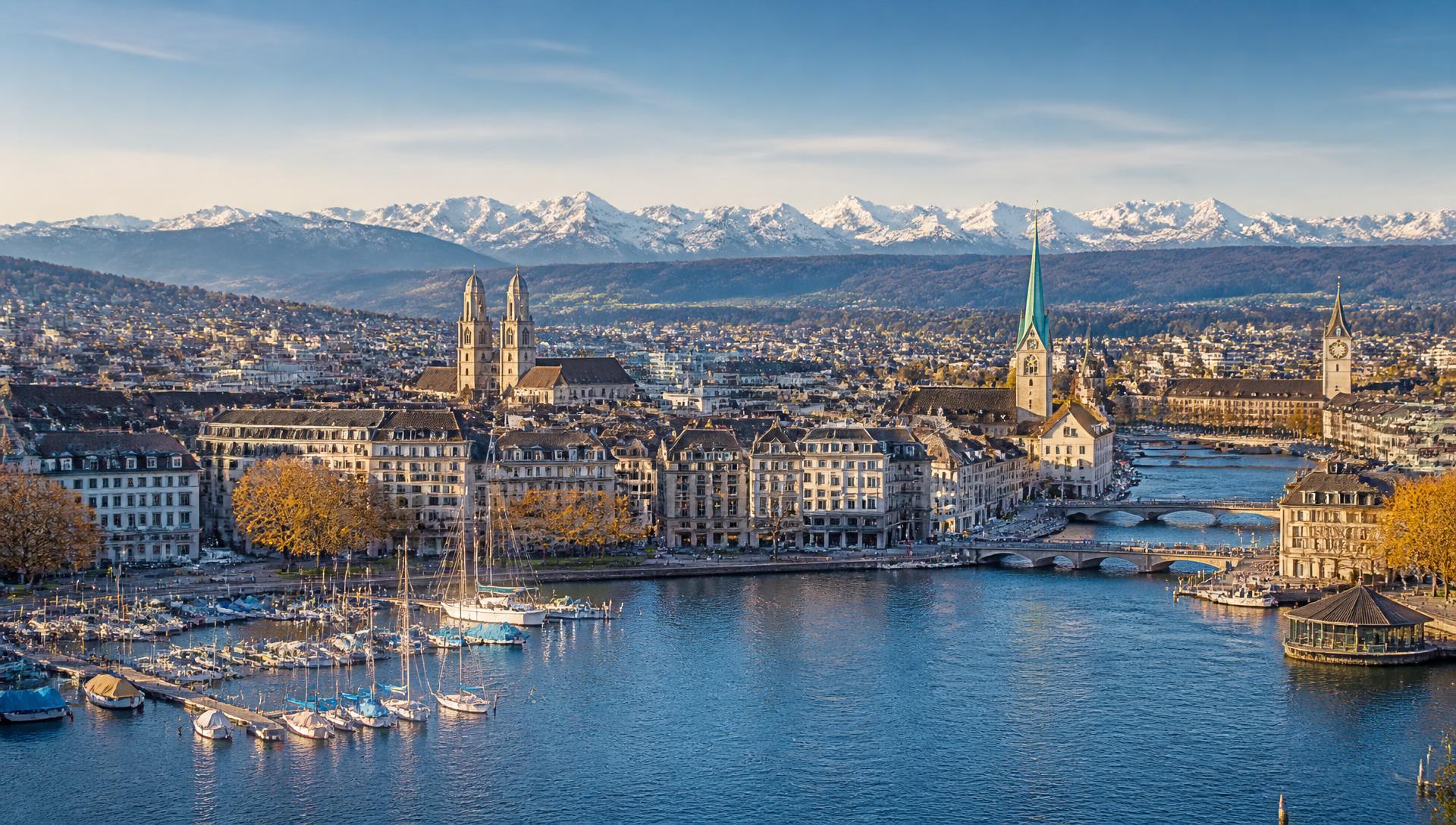 Blick über den Zürichsee auf die Altstadt von Zürich mit Grossmünster, Fraumünster und den Alpen im Hintergrund